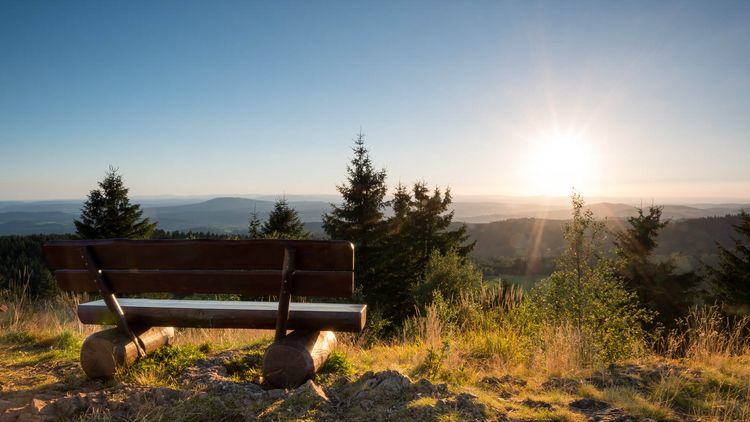 Eine Bank steht mit Blick über das Tal in der herbstlichen Abendsonne