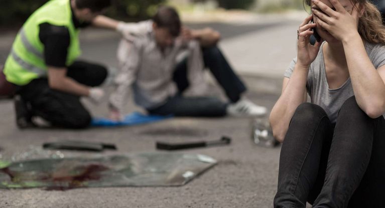 Helfer spricht mit Opfer nach Verkehrsunfall