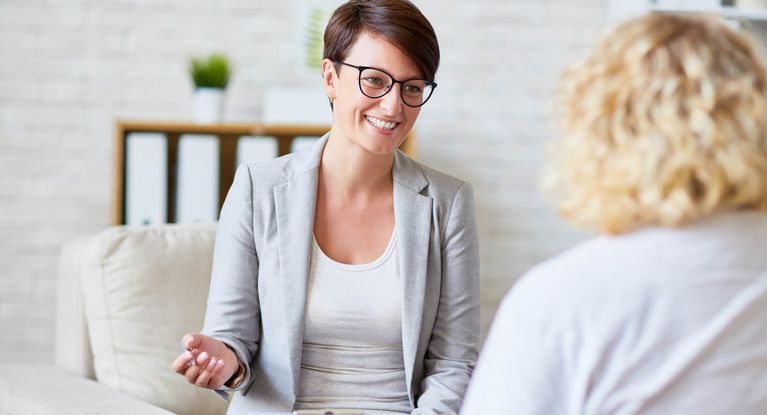 Therapeutin stellt einer Patientin freundlich Fragen