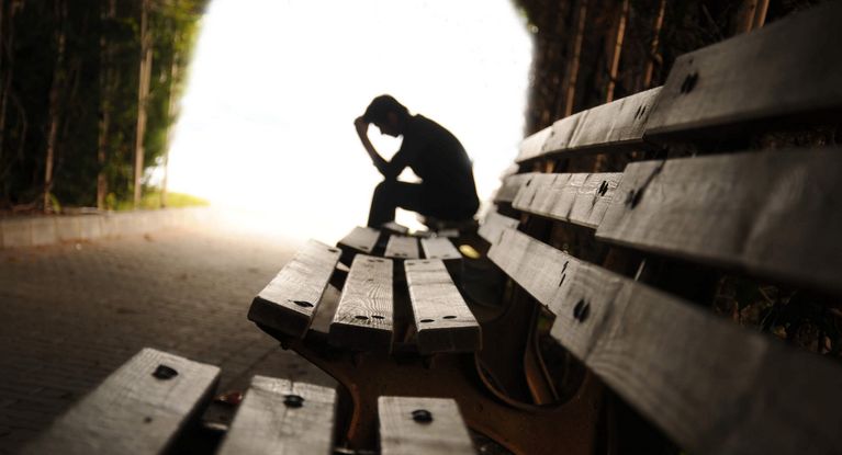 Trauriger und verzweifelter Mann sitzt auf einer Bank